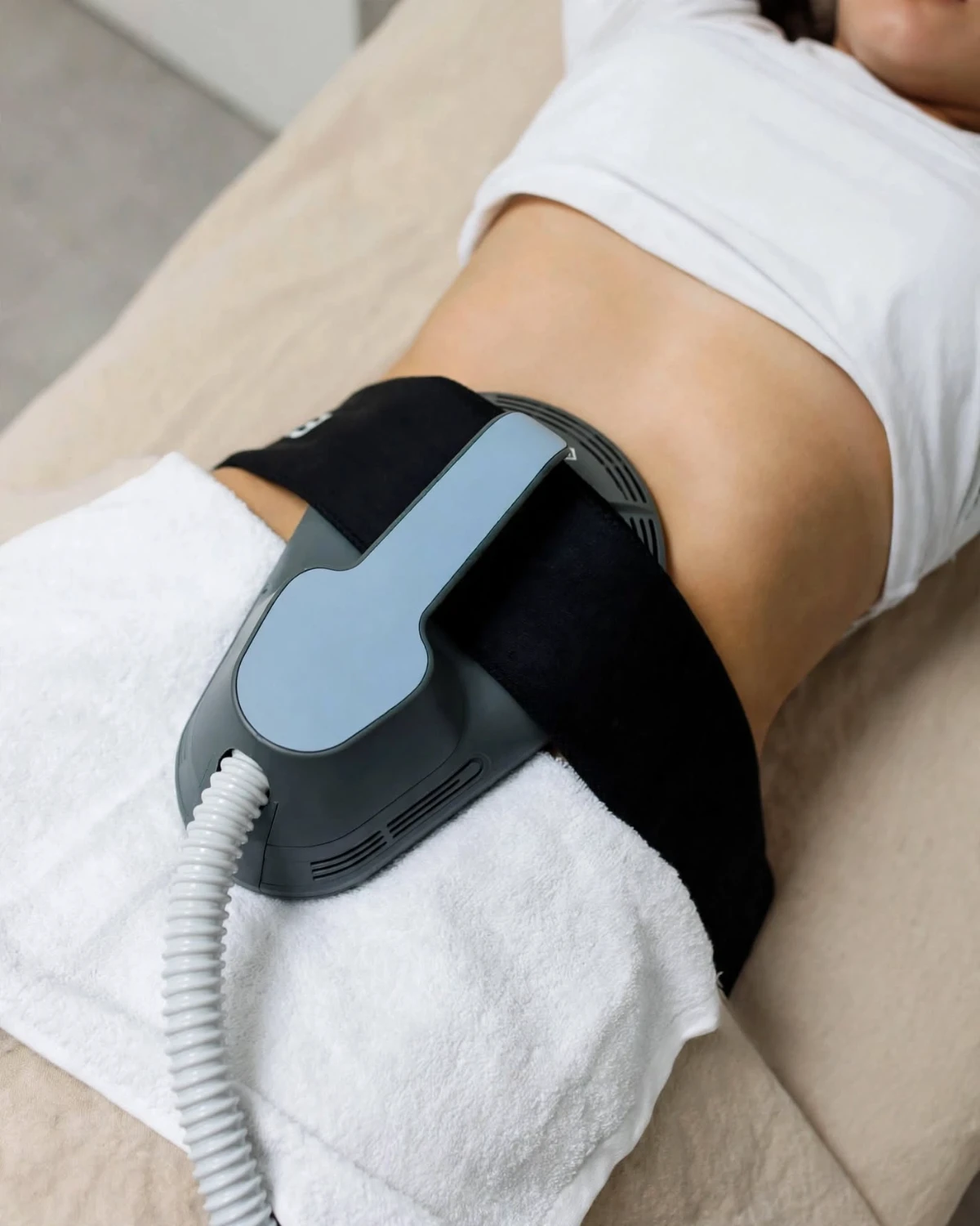 Aplicador de Emsculpt sujetado con banda sobre el abdomen